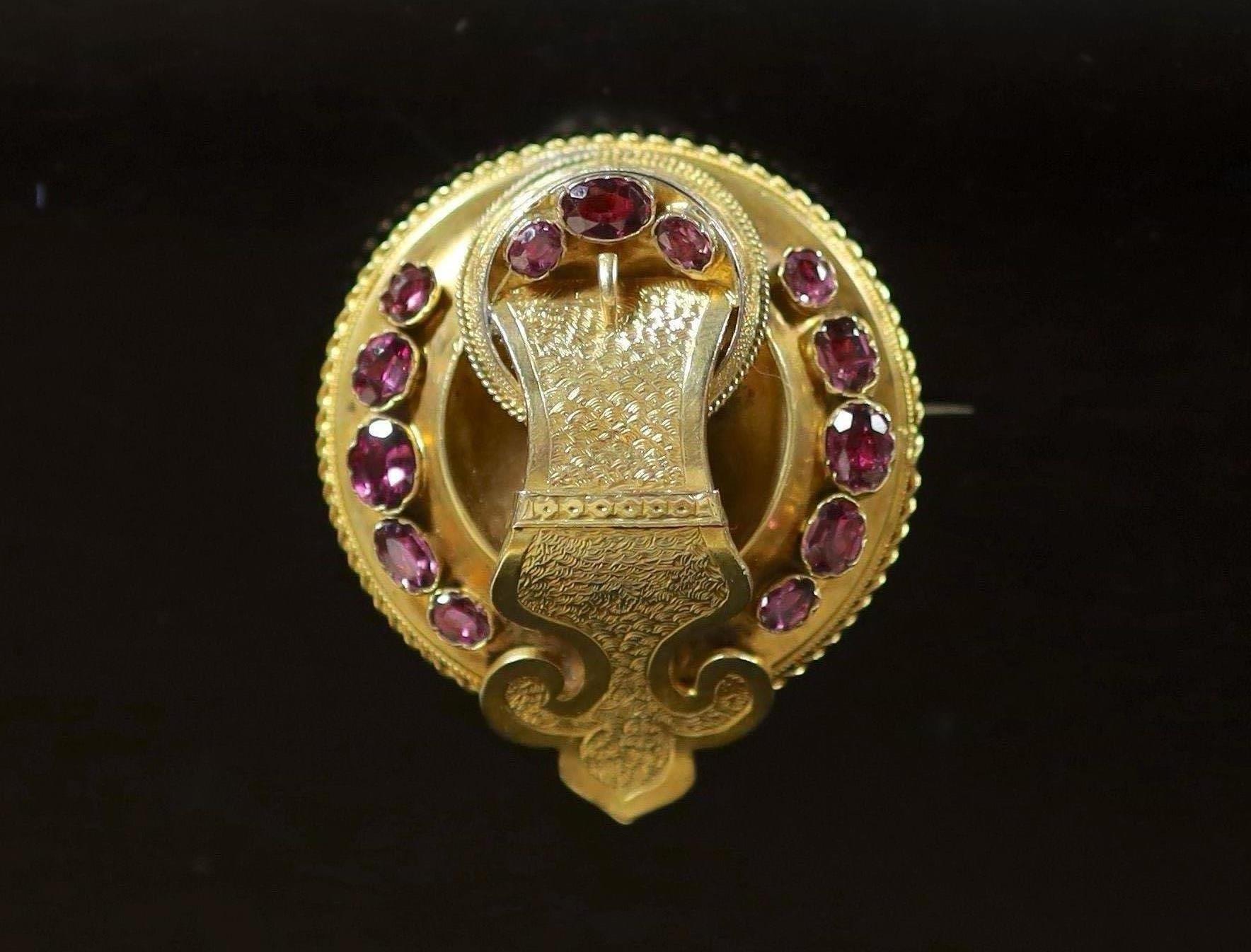 A Victorian gold and garnet set circular 'buckle' brooch